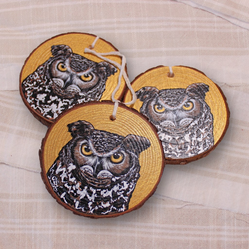 Three round wooden ornaments featuring intricate illustrations of an owl on a gold background.
